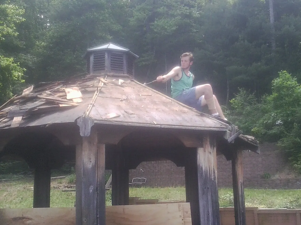 Tearing the old roof off a wooden gazebo before new shakes in Woodbine