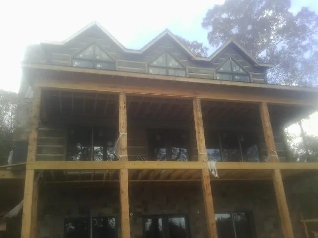Dormers and porch framing on a large log home under construction — Roof Coating work by our crew in Woodbine